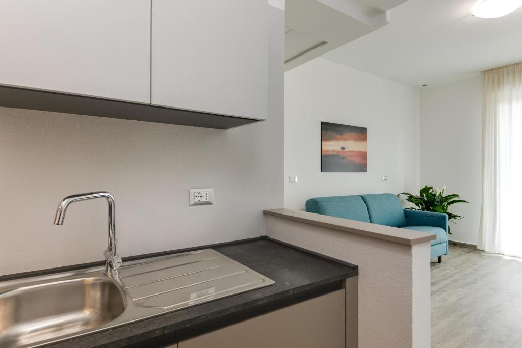 une cuisine avec un évier et une chaise bleue dans l'établissement Elegance Suite Apartments - Siroli Collection, à Cervia