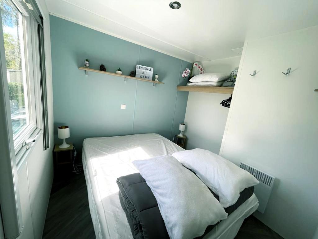 Cette petite chambre comprend un lit avec des draps blancs. dans l'établissement Mobilhome climatisé 6 psn, à Lège-Cap-Ferret