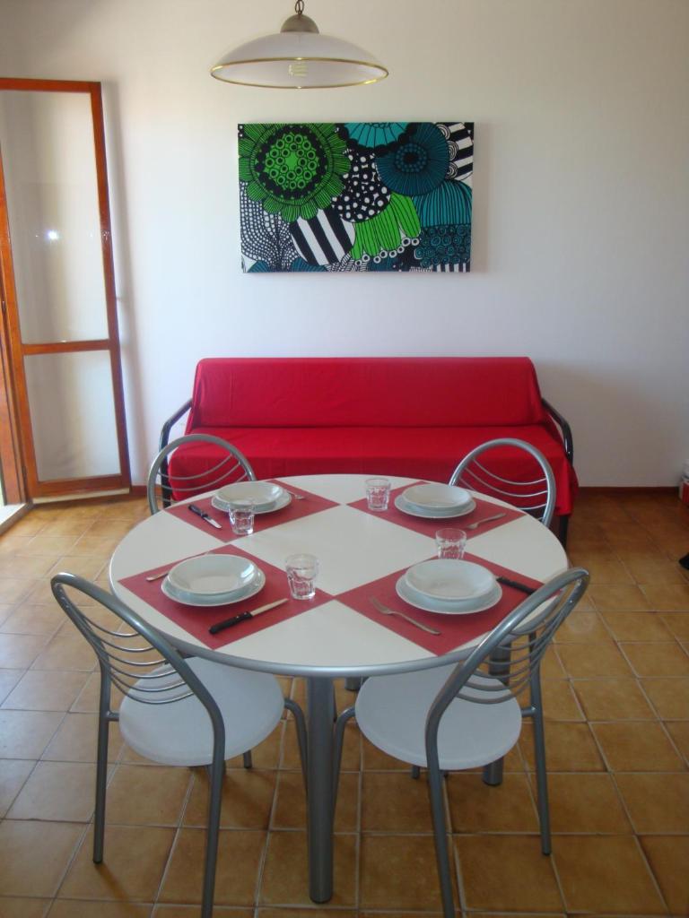 une table avec quatre chaises et un canapé rouge dans l'établissement Aurora Residence, à Lido Adriano