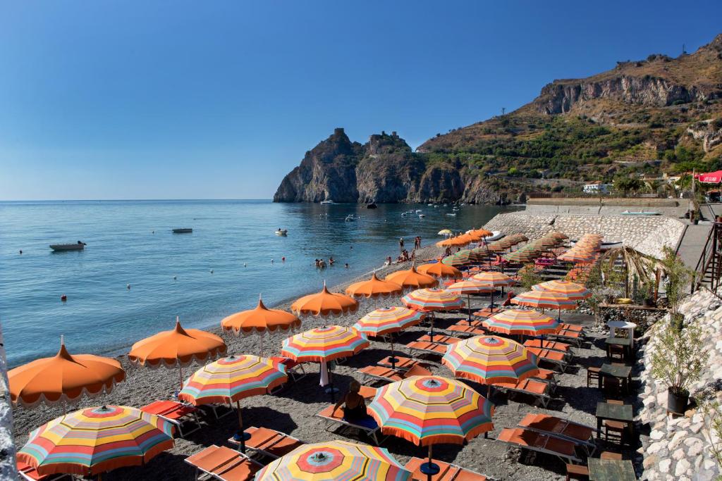 - un bouquet de parasols sur une plage avec l'océan dans l'établissement Hotel Donna Rosa, à SantʼAlessio Siculo