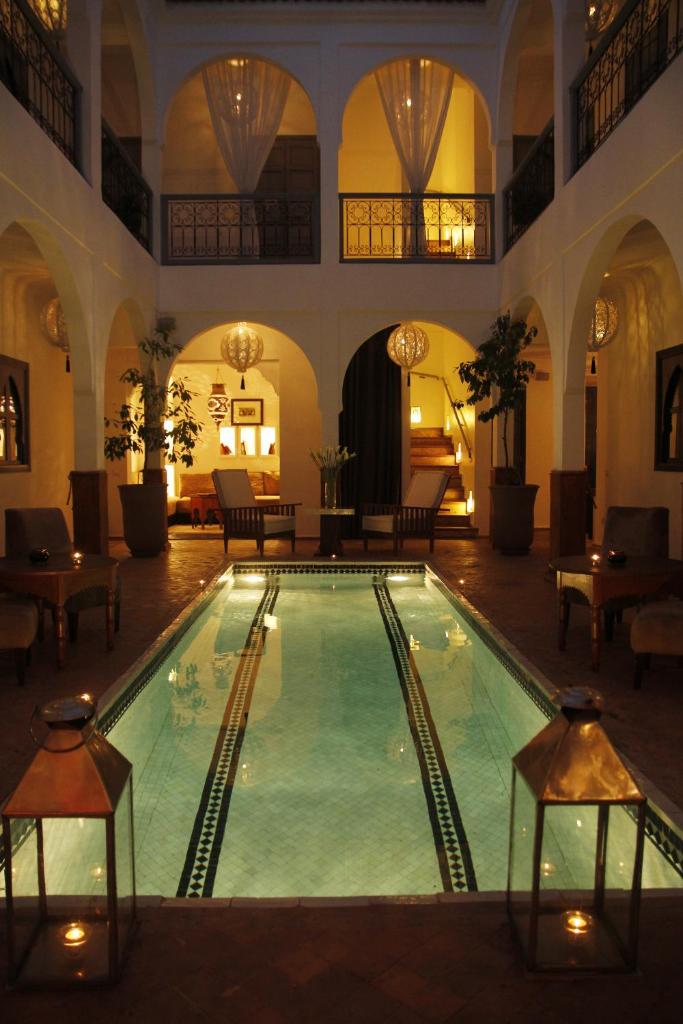 - une grande piscine dans un bâtiment avec des tables et des chaises dans l'établissement Riad Utopia Suites And Spa, à Marrakech