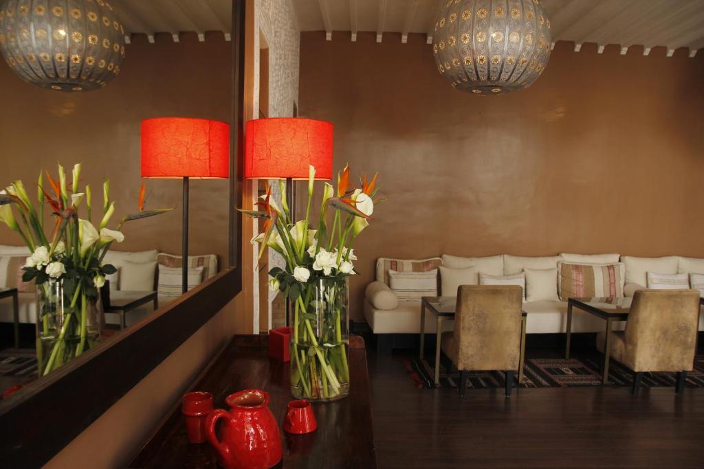 une chambre avec un canapé et une table avec des fleurs dans des vases dans l'établissement Riad Utopia Suites And Spa, à Marrakech