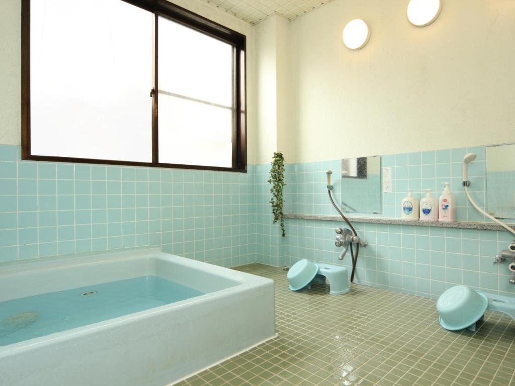 La salle de bains est pourvue de carrelage bleu, d'une baignoire et de toilettes. dans l'établissement Hatoguruma Kawabata, à Nozawa Onsen