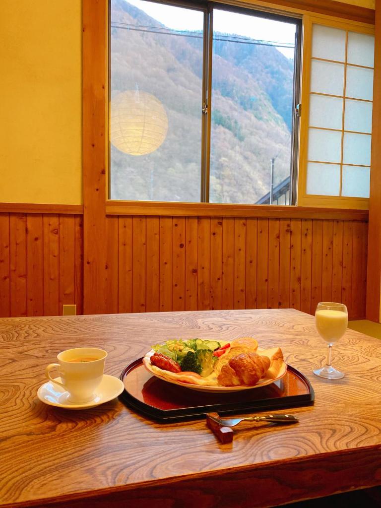 une table avec une assiette de nourriture et un verre de vin dans l'établissement Hakuunsou, à Takayama