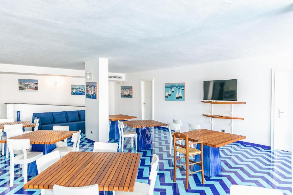 un restaurant avec des tables en bois et des chaises blanches dans l'établissement Hotel Saline, à Palinuro