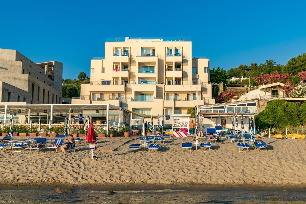 une plage avec des chaises et des parasols et un bâtiment dans l'établissement Hotel Saline, à Palinuro