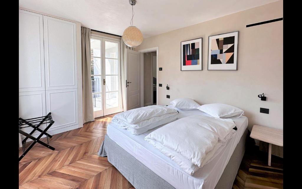 une chambre avec un grand lit avec des draps blancs dans l'établissement Villa Sole Carate Urio – Lake Como, à Carate Urio
