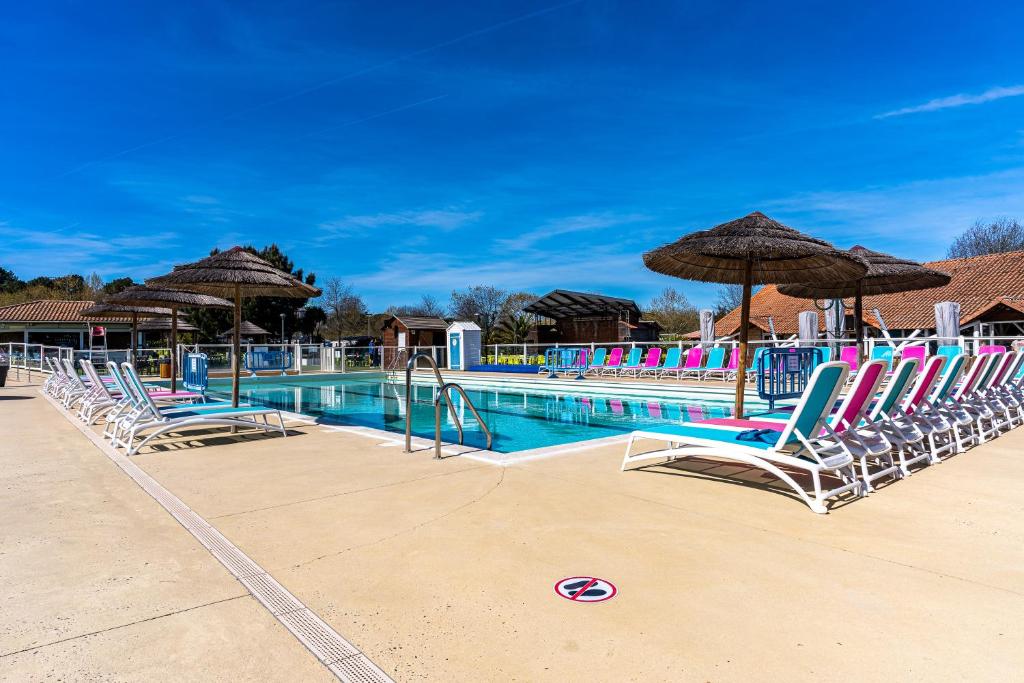 une piscine avec chaises longues et parasols dans l'établissement Mobilehome familial, à Gastes