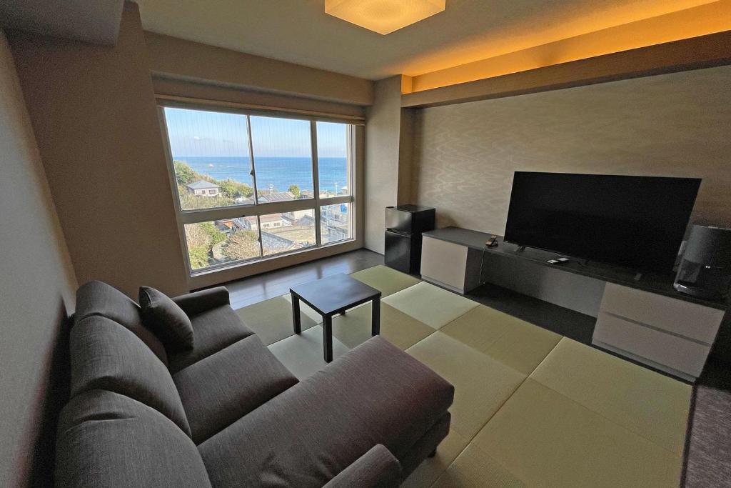 un salon avec un canapé et une grande fenêtre dans l'établissement Ise-Shima Ohtaya Healing Stay, à Toba