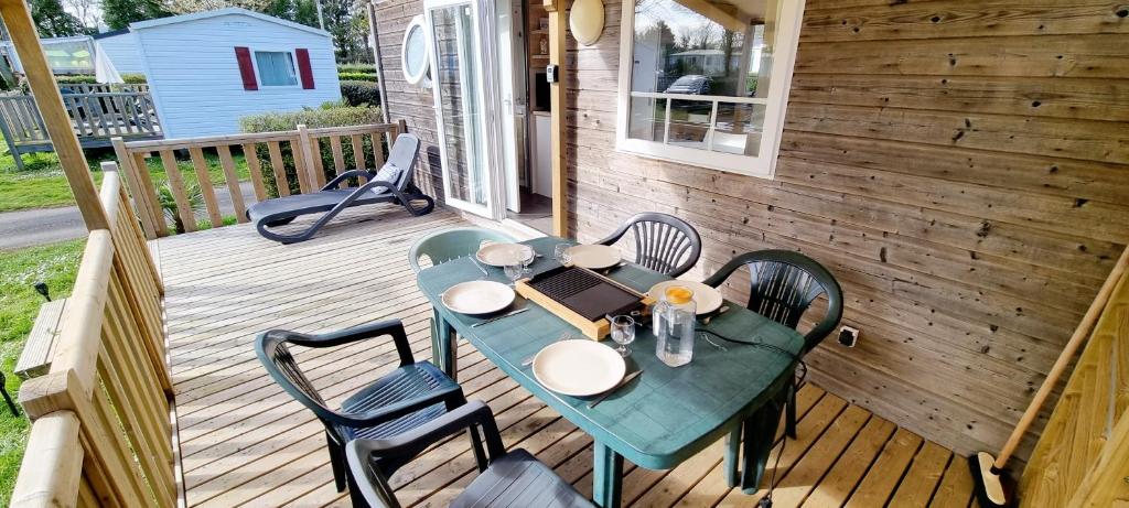 une table et des chaises vertes sur une terrasse en bois dans l'établissement Mobil-home 6 Personnes - Bretagne - Piscine - Plage, à Trégunc