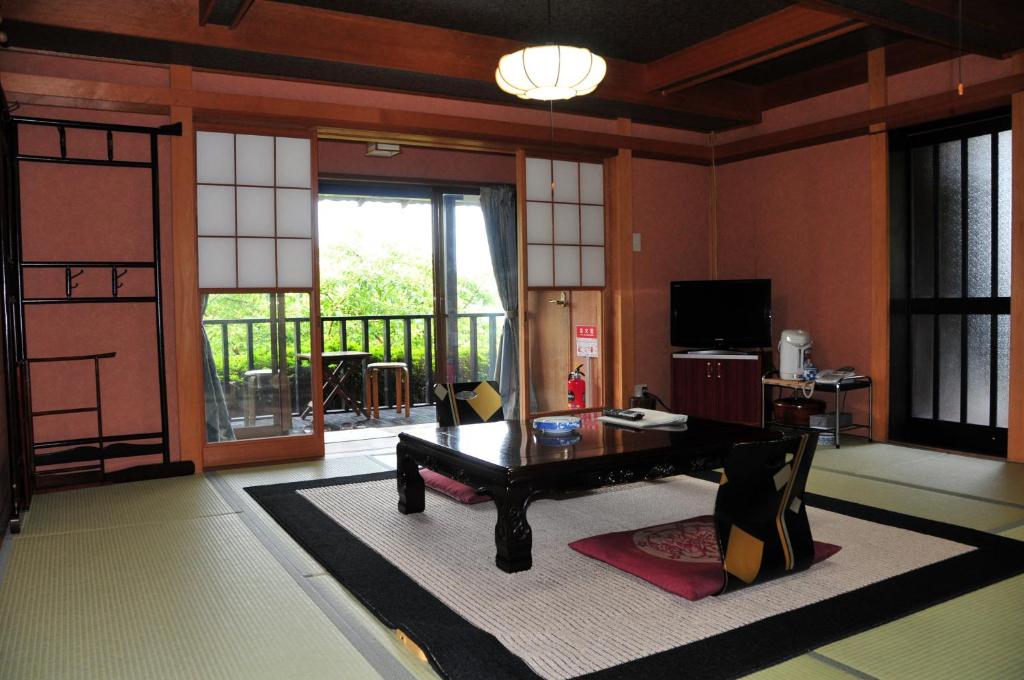 d'un salon avec une table et un balcon. dans l'établissement Yokohama Fujiyoshi Izuten, à Itō
