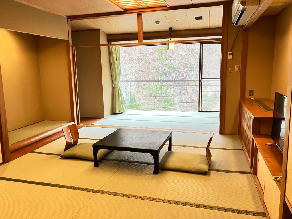 un salon avec une table et une fenêtre dans l'établissement Hotel Yunishigawa, à Nikkō