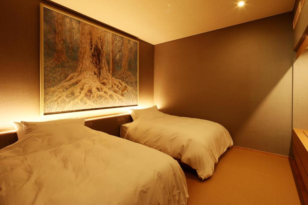 deux lits dans une chambre avec un tableau au mur dans l'établissement Monjusou Shourotei, à Miyazu 37 autres photos