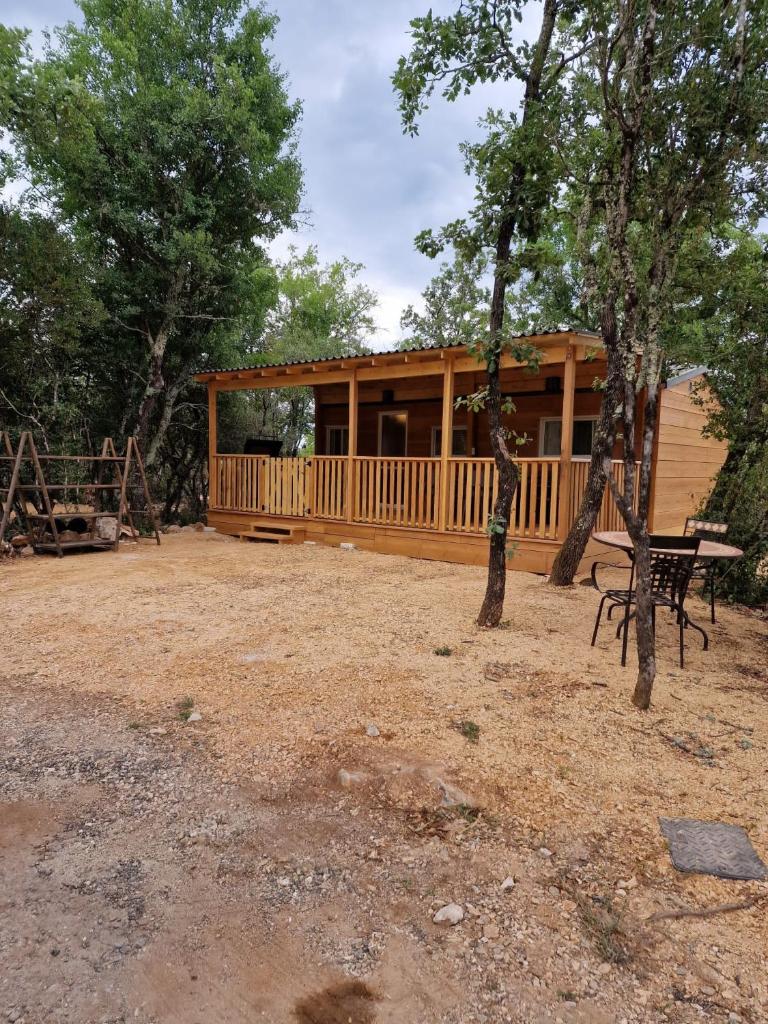 une cabane en bois avec une table de pique-nique devant elle dans l'établissement Gard les Dolmens, à Méjannes-le-Clap
