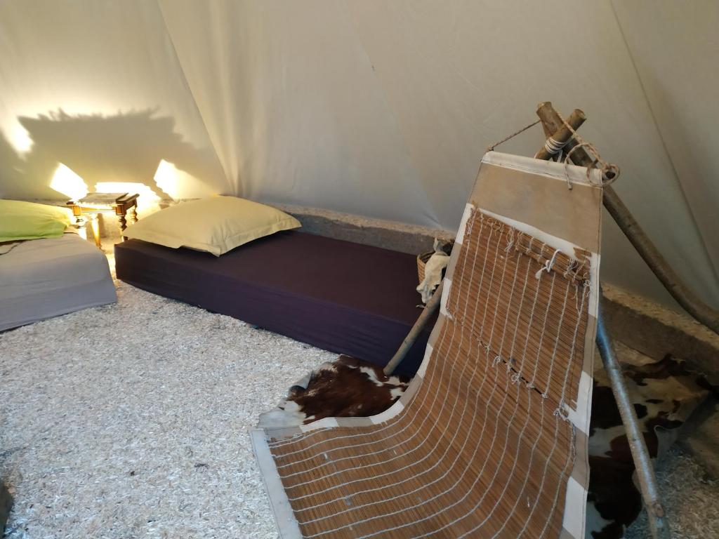 - une chambre avec un lit et un banc dans une tente dans l'établissement Thipi Khola, à Val Couesnon