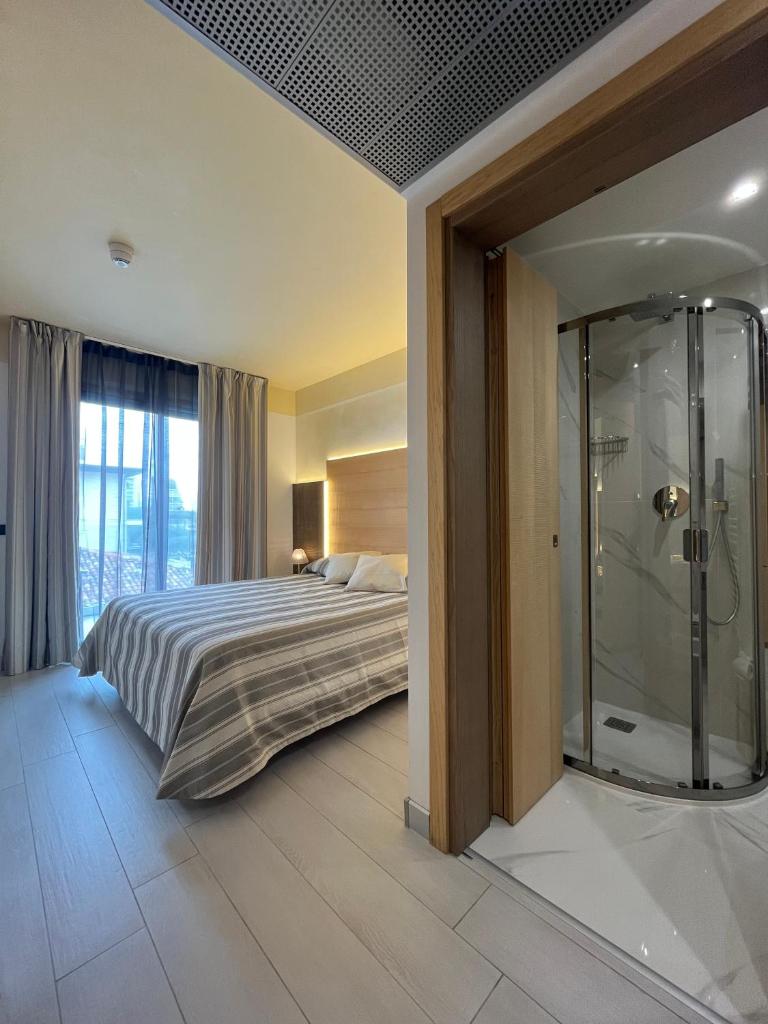 une chambre avec un lit et une douche en verre dans l'établissement Hotel Mare, à Lignano Sabbiadoro 131 autres photos