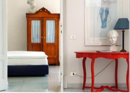Cette chambre comprend une table rouge, un lit et une porte. dans l'établissement Residence Ville Lago Lugano, à Porto Ceresio 31 autres photos