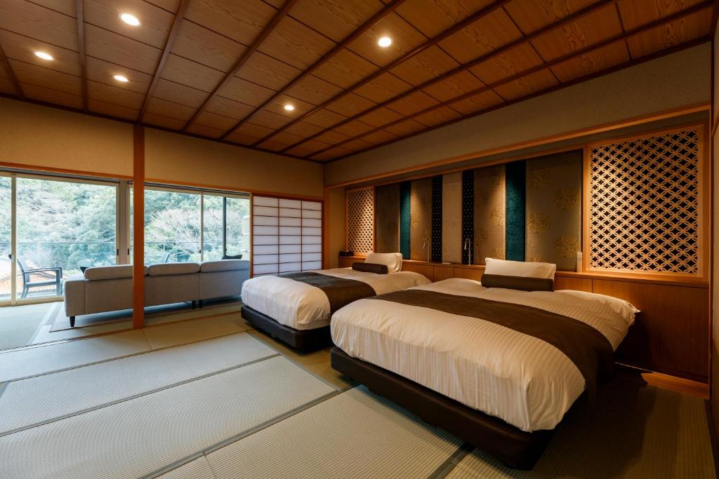 une chambre avec deux lits et un canapé et des fenêtres dans l'établissement Tachibana Shikitei, à Kaga