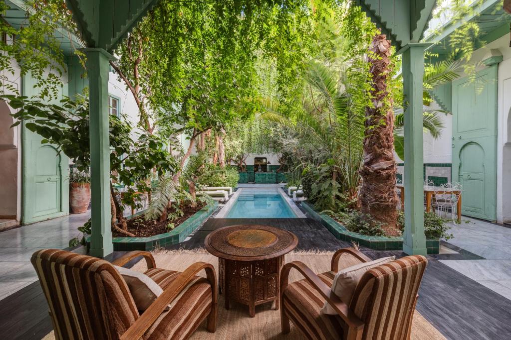 - une piscine intérieure avec des chaises, une table et des arbres dans l'établissement Riad Kitula, à Marrakech