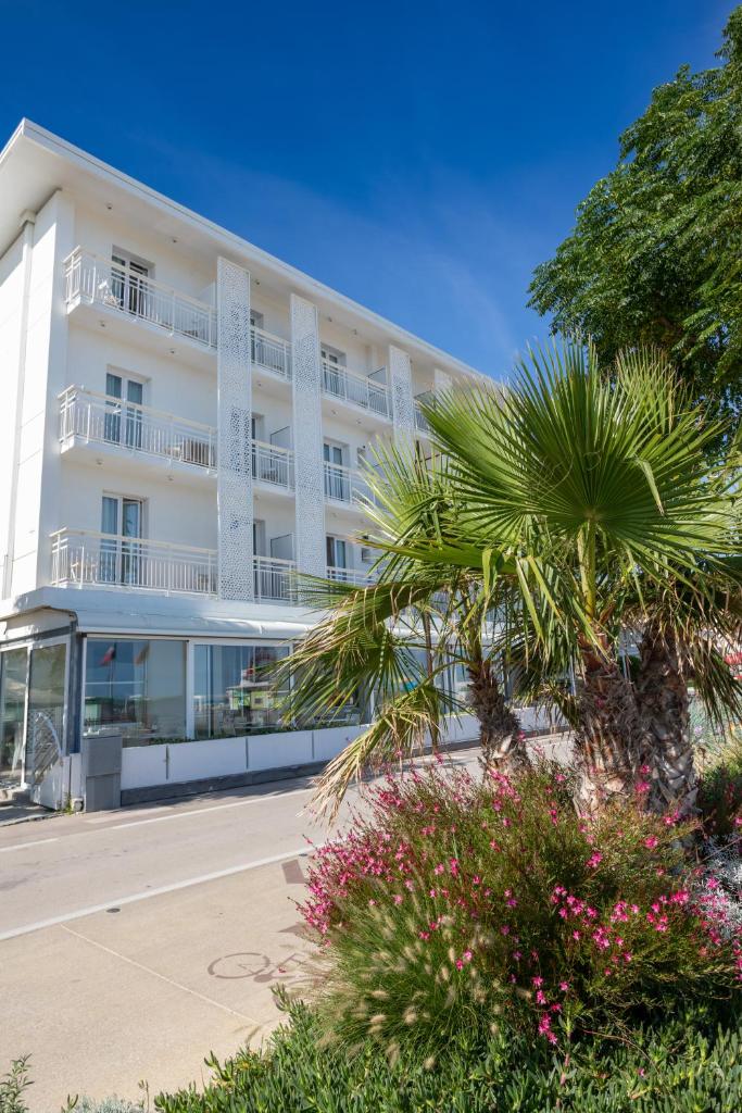 un bâtiment blanc avec un palmier devant dans l'établissement Hb Hotels Orchidea Blu, à Rimini