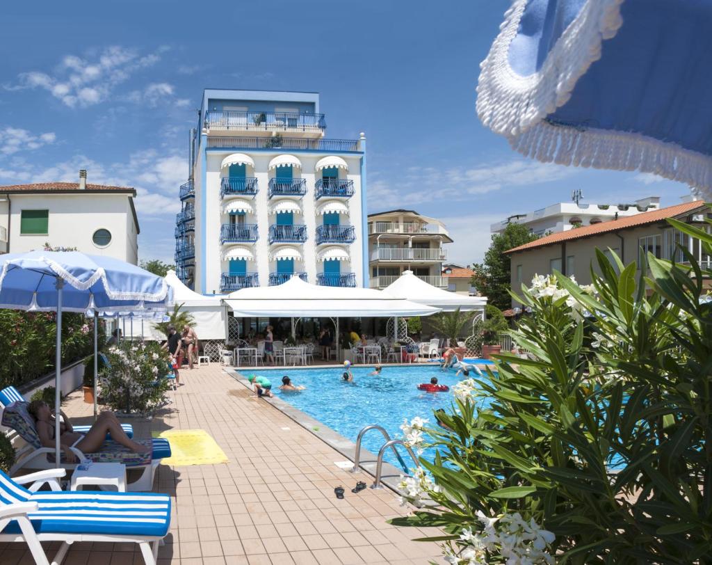 une piscine avec un hôtel en arrière-plan dans l'établissement Hotel Plaza Esplanade, à Lido di Jesolo