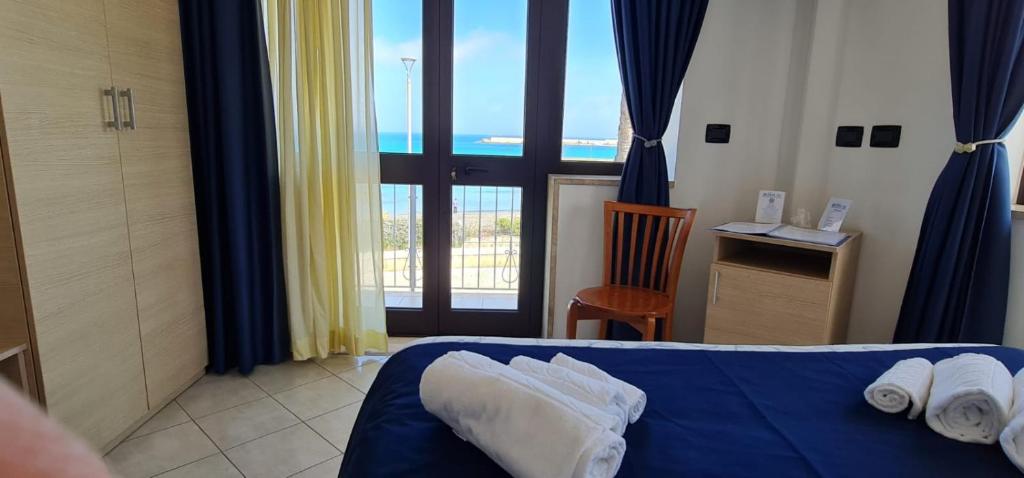 Cette chambre d'hôtel dispose d'un lit bleu et d'un balcon. dans l'établissement Hotel Profumo Di Mare, à Otrante