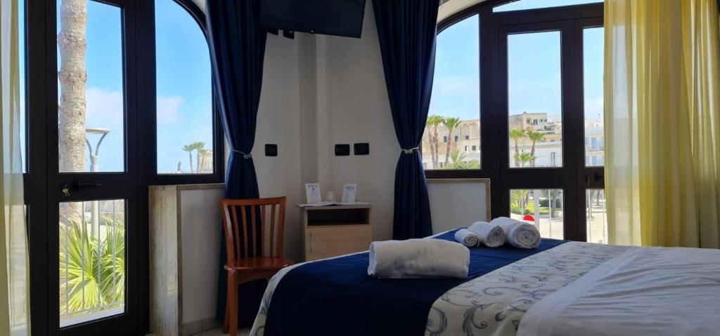 - une chambre avec un lit doté de draps bleus et de grandes fenêtres dans l'établissement Hotel Profumo Di Mare, à Otrante
