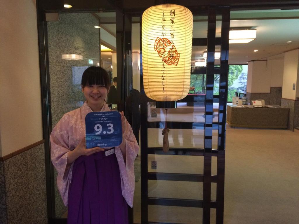 une femme debout devant une porte tenant une horloge dans l'établissement Funaya, à Matsuyama 37 autres photos