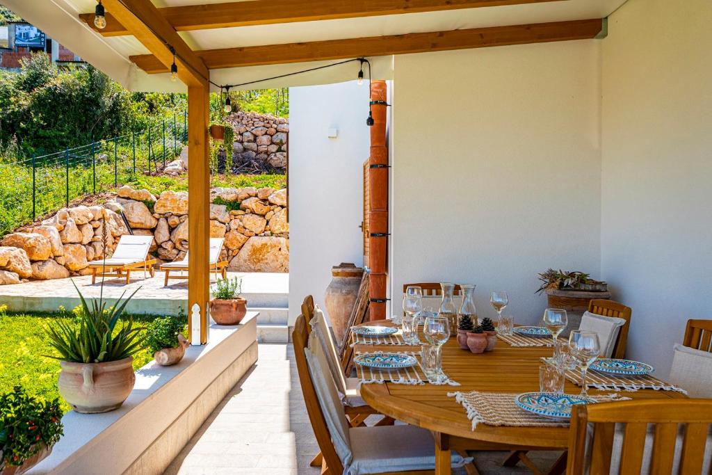 une table et des chaises en bois sur une terrasse dans l'établissement Villa Bellacosa con Piscina Privata vista mare, à Castellammare del Golfo
