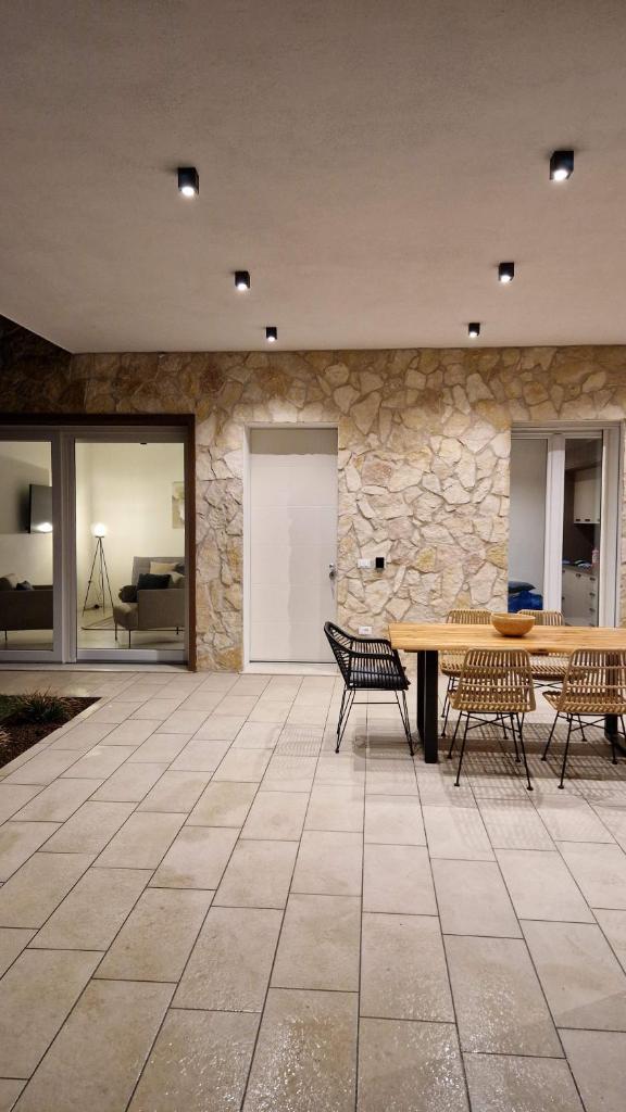 un patio avec une table et des chaises et un mur en pierre dans l'établissement Villa My Lagozise, à Pacengo di Lazise