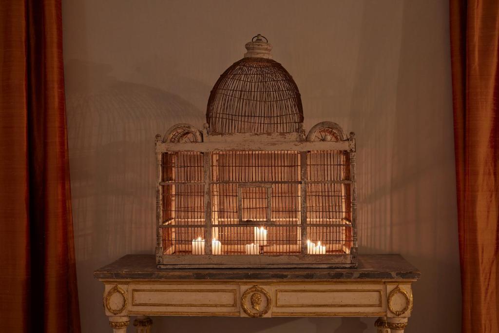 une cage à oiseaux posée sur une table devant un miroir dans l'établissement Palazzo Vecchio Taormina, à Taormine 30 autres photos