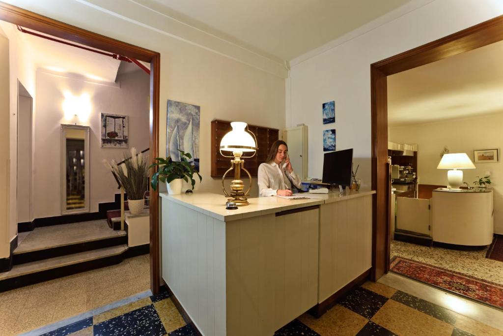 une femme assise à la réception dans le hall dans l'établissement Hotel Villa Giulia, à Laigueglia