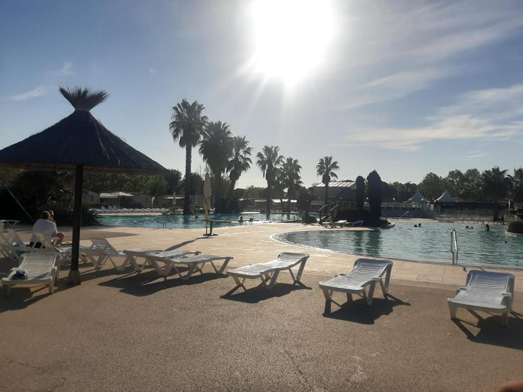une piscine avec un tas de chaises et un bain de soleil dans l'établissement LA CARABASSE CP90, à Vias 5 autres photos