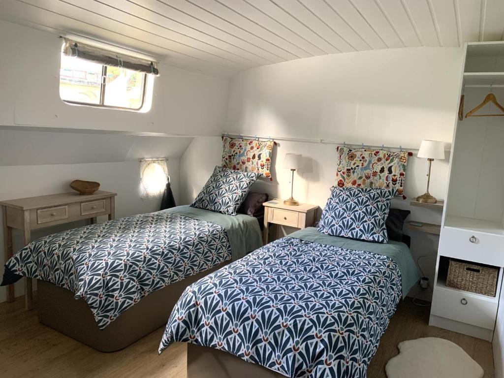 une petite chambre avec deux lits et une fenêtre dans l'établissement Péniche GEMJO, à Castelsarrasin
