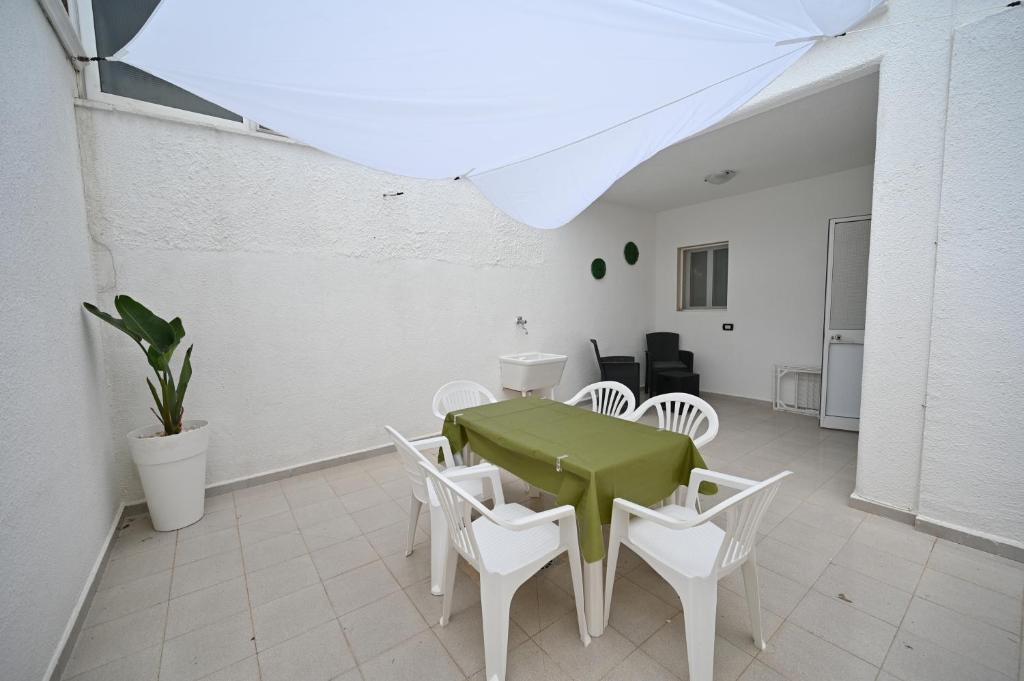 une salle à manger avec une table verte et des chaises blanches dans l'établissement villa adua, à Torre Santa Sabina