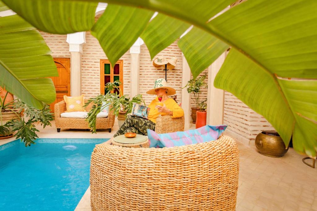 une personne portant un chapeau assise sur une chaise à côté d'une piscine dans l'établissement SABOR SAFRA, à Marrakech