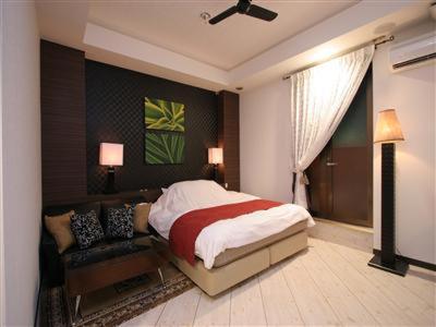 une chambre avec un lit et un canapé dans l'établissement 本庄バニラリゾート, à Ishigami