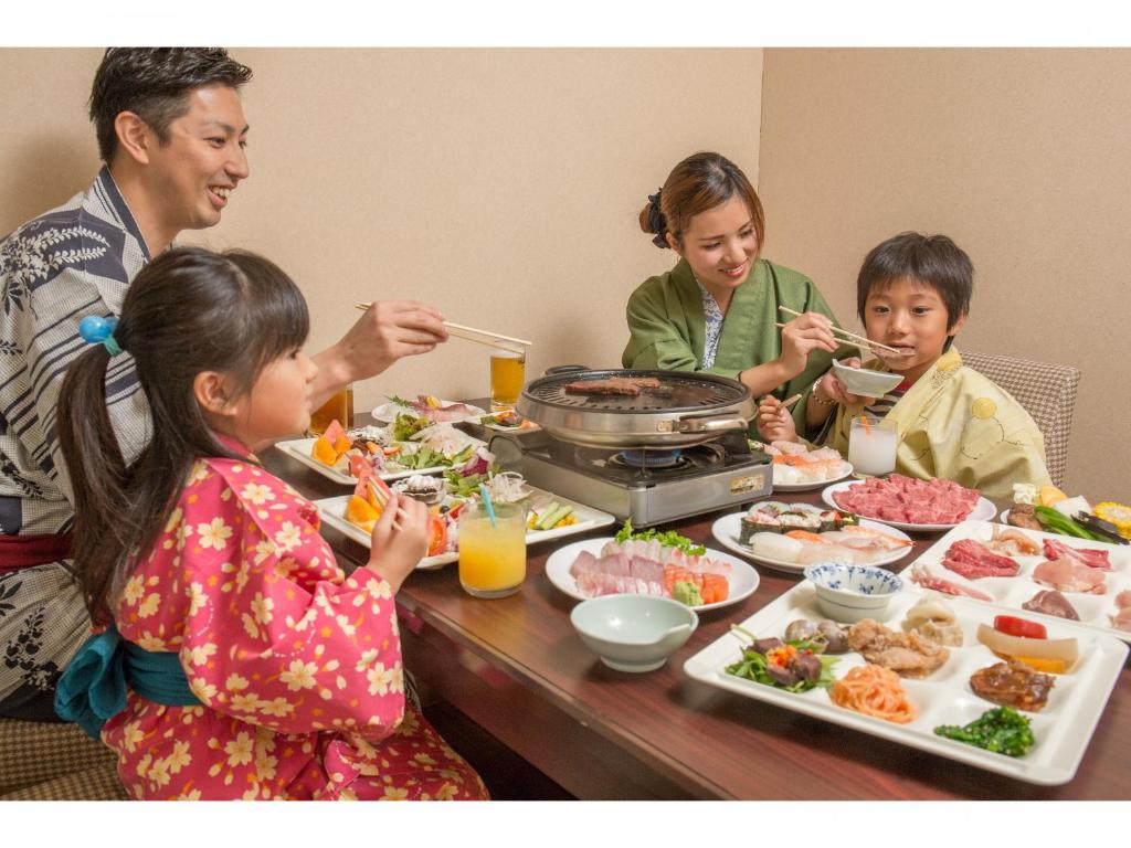 un groupe de personnes assises à une table en train de manger dans l'établissement Yumeoi-so, à Aso