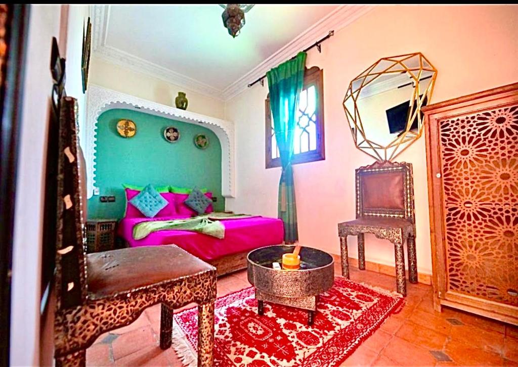 un salon avec un lit et une chaise dans l'établissement Riad Maison Aicha, à Marrakech