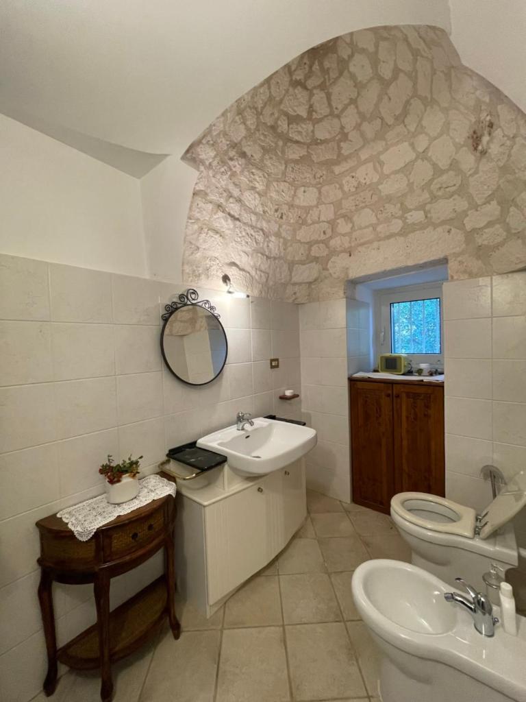une salle de bain avec un lavabo, des toilettes et un miroir dans l'établissement Trullo Trullallero, à Martina Franca 42 autres photos