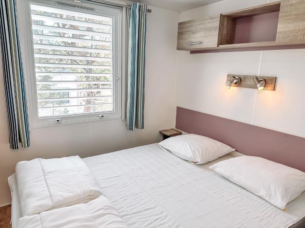 une chambre avec un lit blanc et une fenêtre dans l'établissement 3 bedroom Chalets Camping Leï Suves - JoyCasa, à Roquebrune-sur Argens