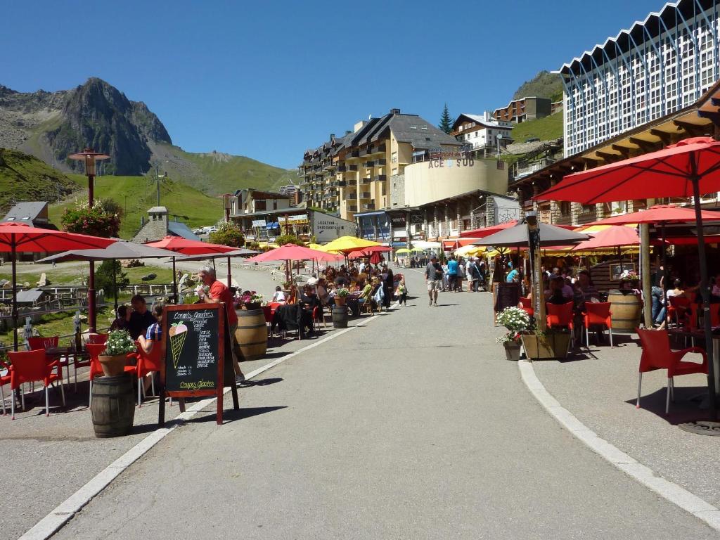 une rue avec des tables, des chaises et des parasols dans l'établissement Résidence Mer & Golf Tourmalet, à La Mongie