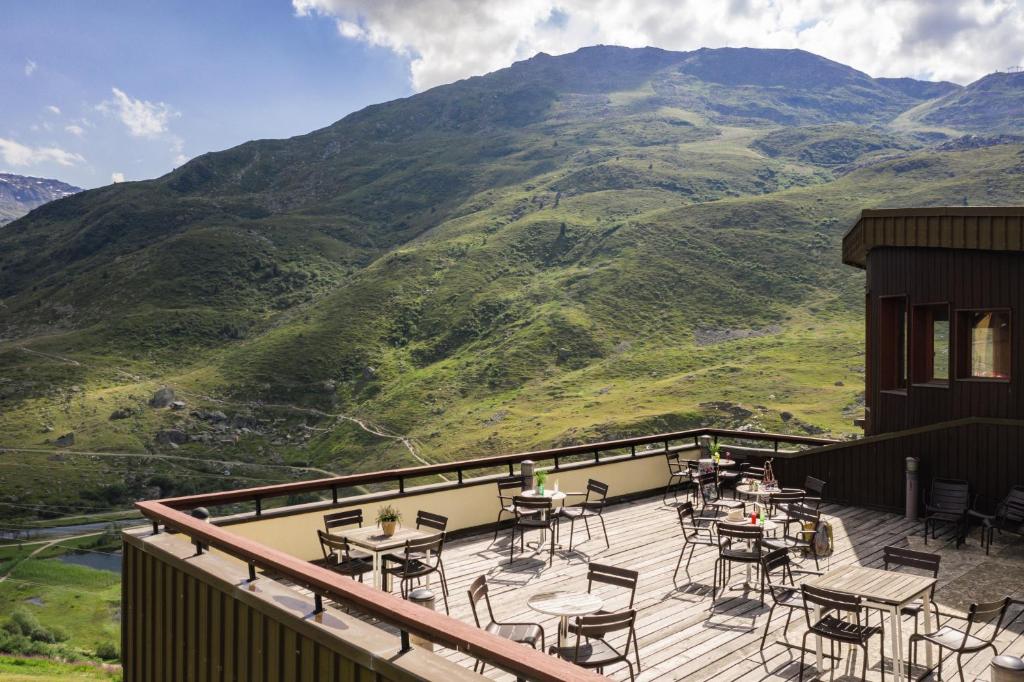 d'un balcon avec des tables et des chaises et des montagnes en arrière-plan. dans l'établissement Hôtel Les Menuires Les Bruyères, aux Menuires
