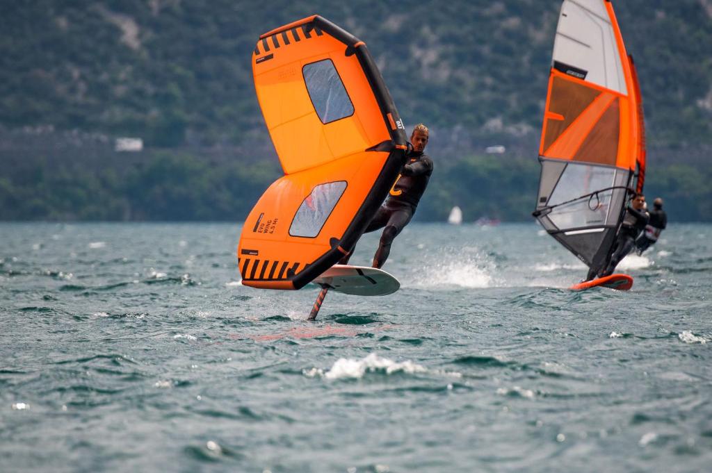 deux personnes font de la planche à voile sur un plan d'eau dans l'établissement Surf Hotel Pier - Montagnoli Group, à Limone sul Garda