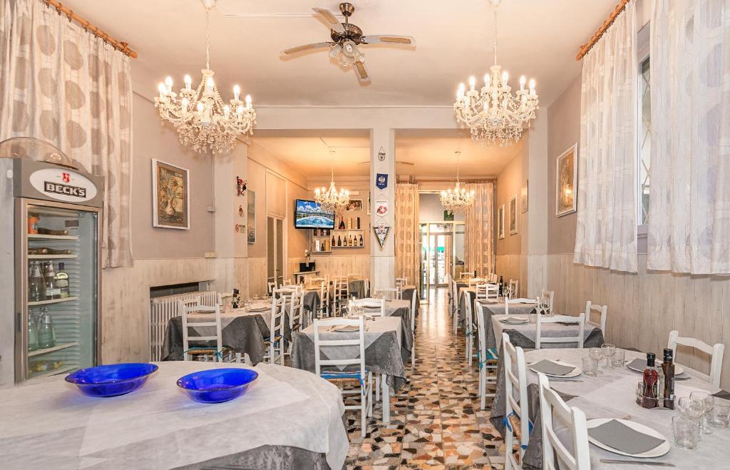 un restaurant avec des tables et des chaises blanches et des lustres dans l'établissement Hotel Stella Del Mare, à Viareggio