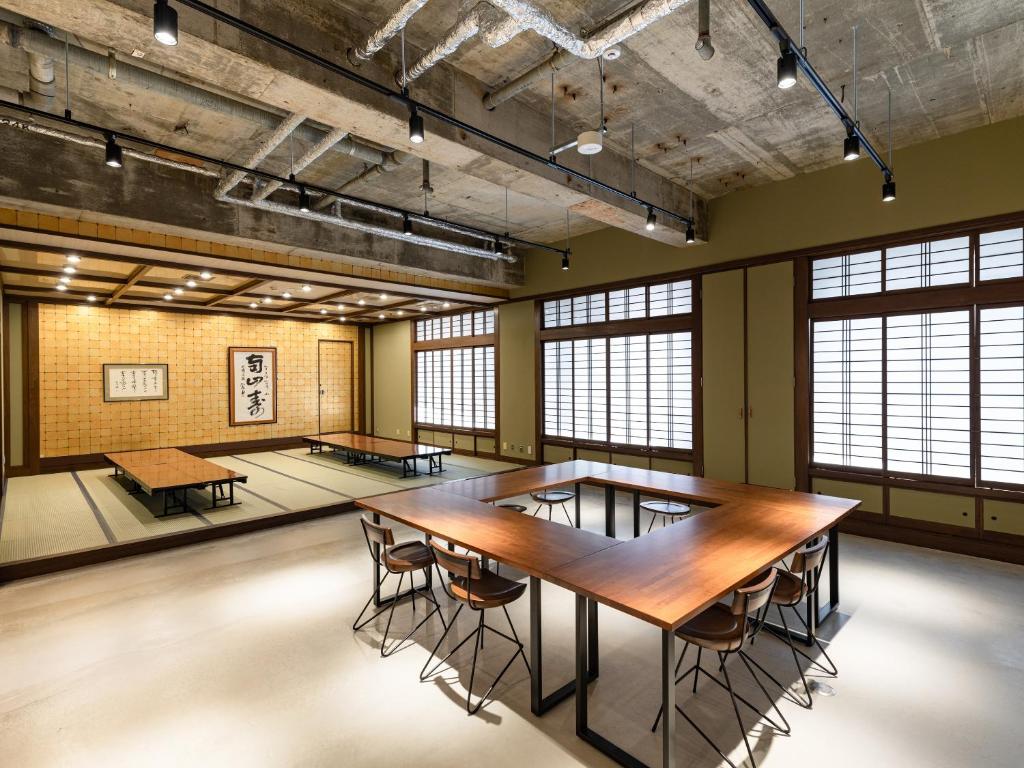 une grande pièce avec des tables, des chaises et des fenêtres dans l'établissement Kaneyoshi Ryokan, à Osaka 37 autres photos