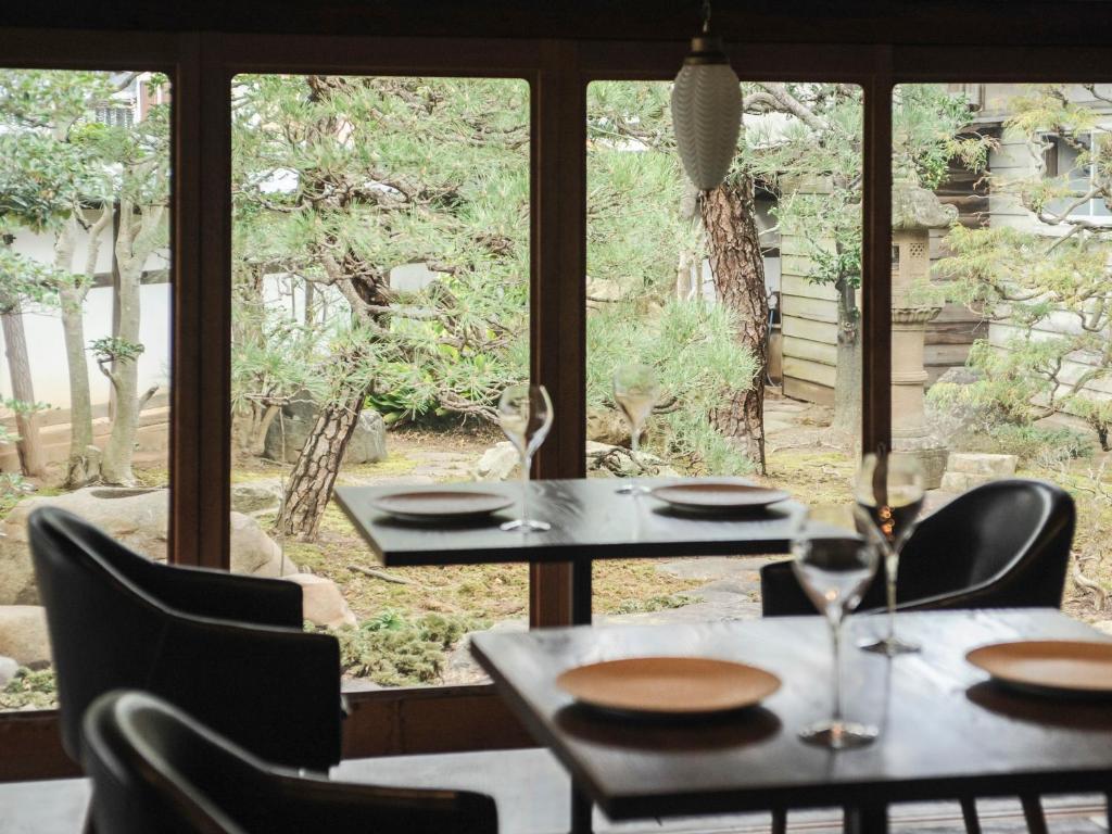 deux tables et des chaises devant une fenêtre dans l'établissement NIPPONIA Izumo Taisha Shrine Town, à Izumo