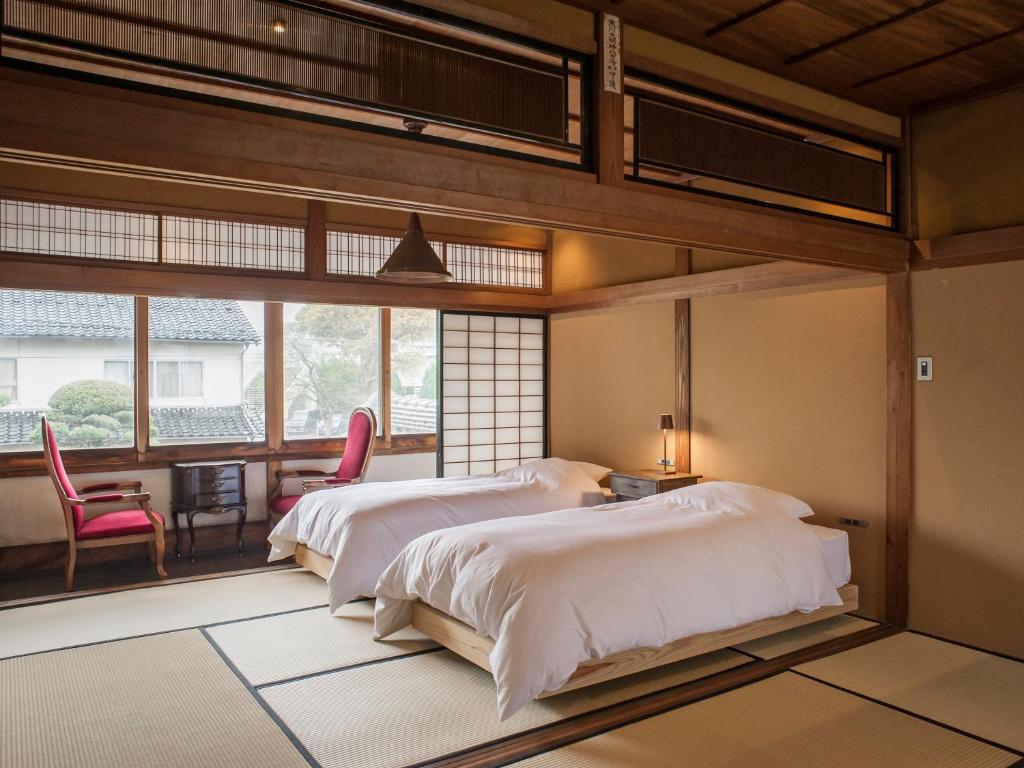 une chambre avec deux lits et une table et des chaises dans l'établissement NIPPONIA Izumo Taisha Shrine Town, à Izumo