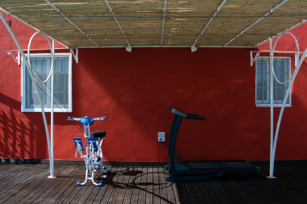 - une salle de sport avec deux vélos d'exercice devant un mur rouge dans l'établissement Casale dello Zio, private pool by IL PUMO DI PUGLIA, à Castellana Grotte
