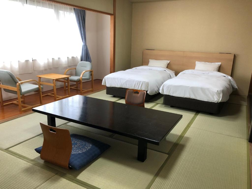 une chambre d'hôtel avec deux lits, une table et des chaises dans l'établissement Ureshino Onsen Yusyuku Sarayama, à Ureshino